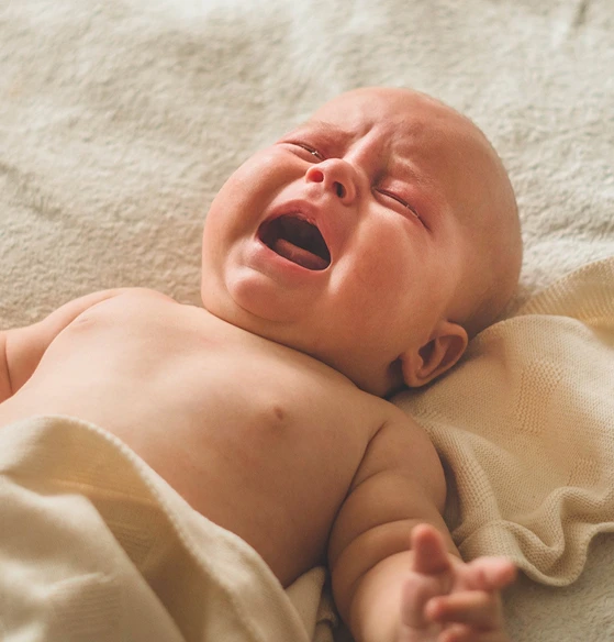 Bebê chorando deitado na manta