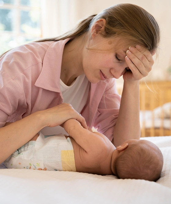 Mãe cansada deitada ao lado do bebê